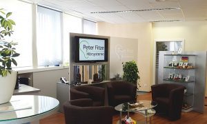 Modernes Hörakustik-Fachgeschäft mit Wartebereich, Pflanzen und Beratungstheke.